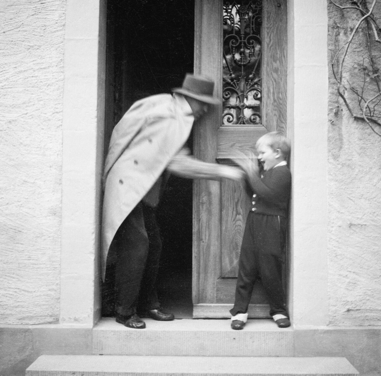 Photo noir blanc de Ramuz jouant avec son petit-fils Guido Olivieri dans l'embrasure de la porte de La Muette. L'image est joyeuse.